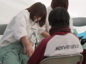 神戸サウナのスタッフが椅子に座った競技者にマッサージを行っている